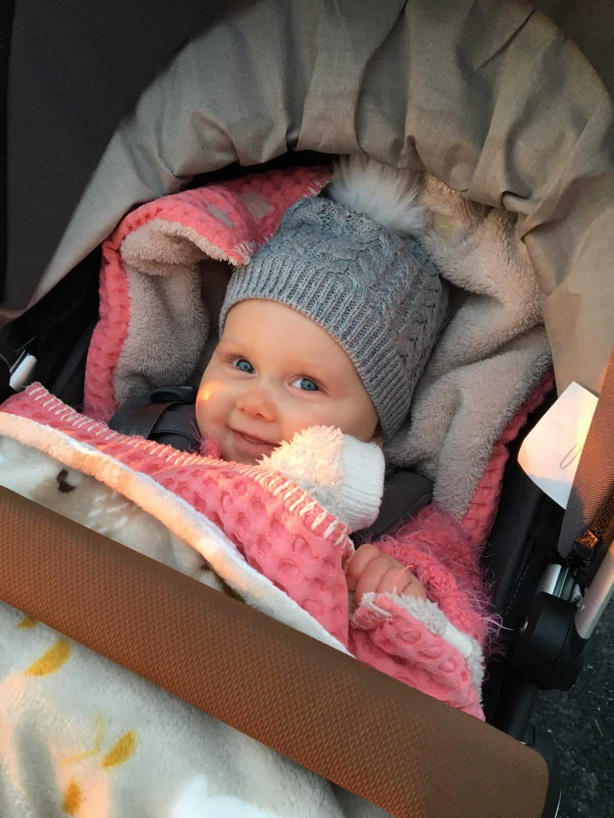 Baby lacht in de kinderwagen buiten